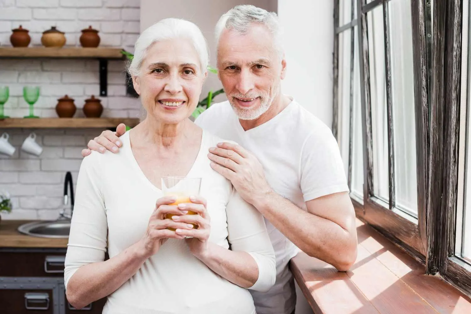 Smiling older couple standing together in their kitchen